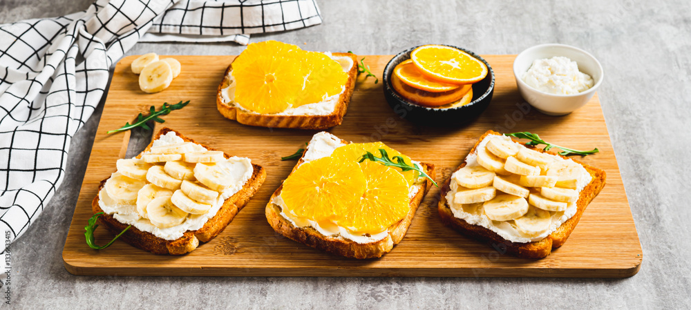 Crispy sandwiches with cottage cheese and fruits on a board on a table web banner