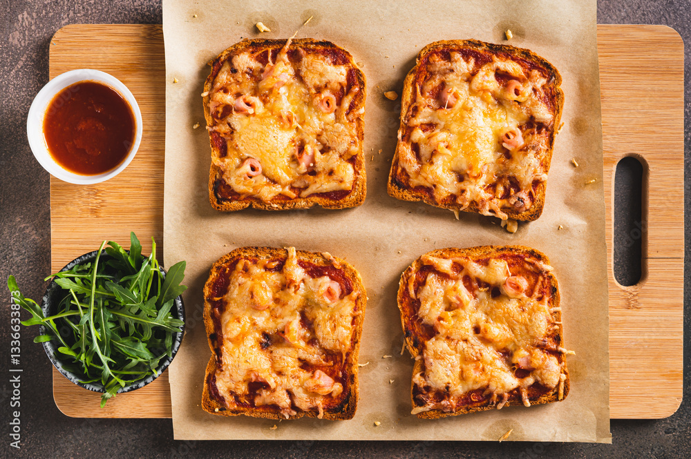 Close up of baked sandwiches with bacon, cheese and tomato sauce on a board on a table top view