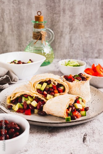 Obraz na płótnie Salad of beans, cucumber and pepper in lavash rolls on a plate on the table vertical view w salonie