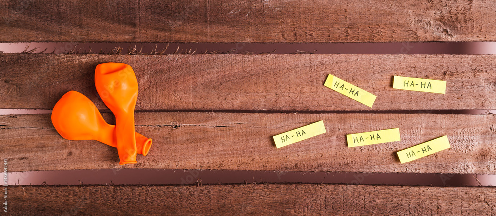 Happy April Fools Day, balloons and funny notes on wooden top view web banner