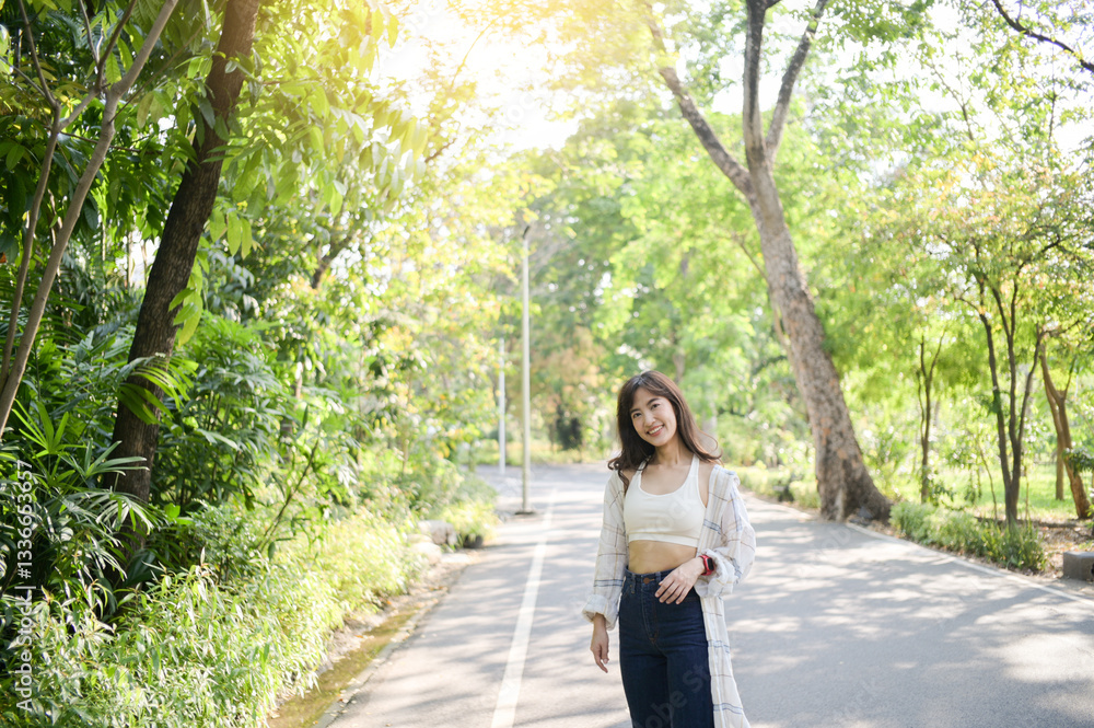 Asian woman enjoying summer outdoors, breathing fresh air in lush green park, smiling and feeling relaxed under warm sunlight Asian woman enjoying summer outdoors, breathing fresh air in lush green park, smiling and feeling relaxed under warm sunlight
