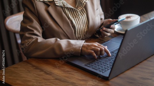 Wallpaper Mural Businesswoman working with laptop on wooden desk, holding smartphone for communication, stressed work and investment decision. Torontodigital.ca