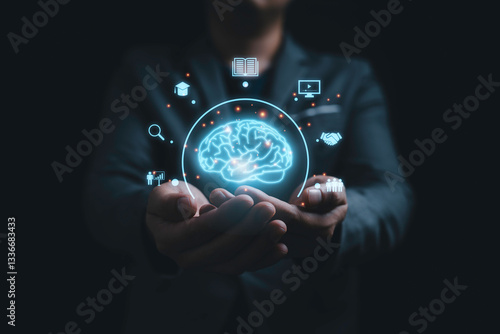 Businessman holding virtual glowing Brain with knowledge icons for study concept.
