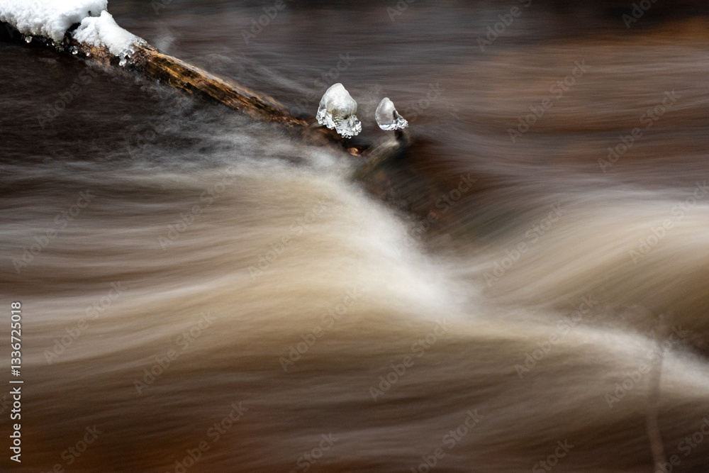 close-up view of a wild wild river, long exposure, blurred water, frozen ice formations in the river stream