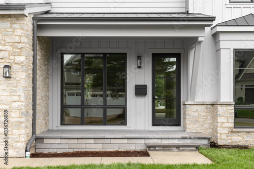 Canvas Print A modern farmhouse front door detail with large black framed windows and front door, grey board and batten siding, and stone front porch and siding