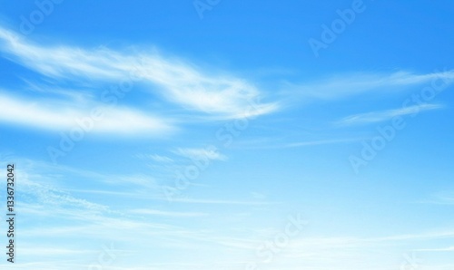A bright, clear sky with soft white clouds drifting lightly across the vast blue expanse above the horizon