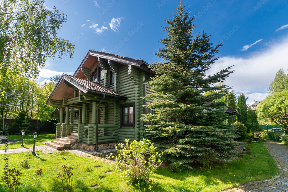 A delightful summer landscape on a private territory with a two-storey wooden house .Sunny, clear day. A delightful summer landscape on a private territory with a two-storey wooden house .Sunny, clear day.