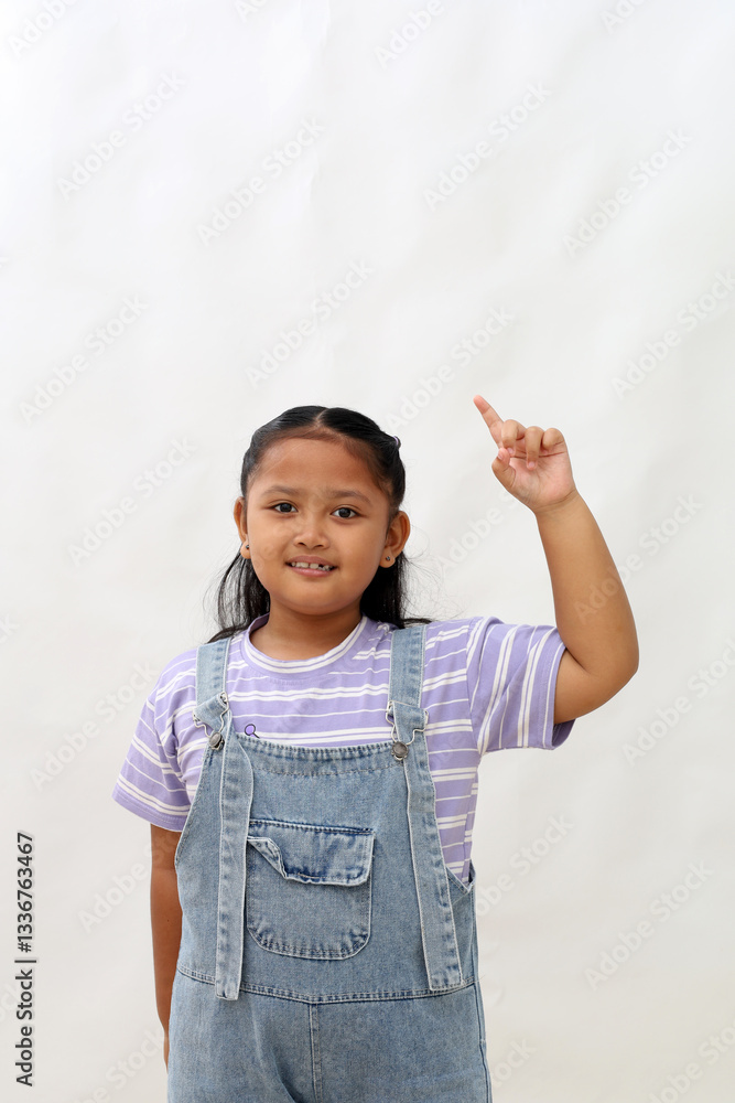 Happy asian little girl standing while pointing up or showing one finger. Isolated on white Happy asian little girl standing while pointing up or showing one finger. Isolated on white