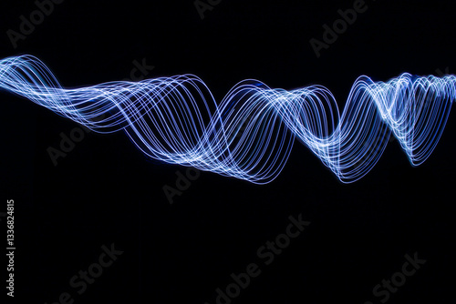 A long exposure photograph of vibrant electric blue light in swirl patterns of motion against a black background