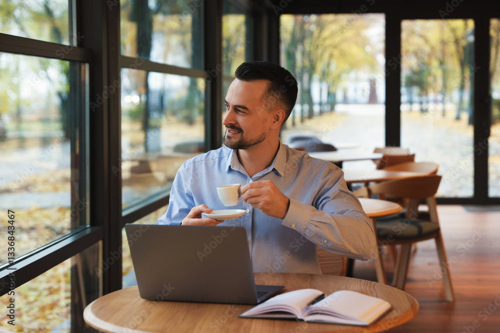 Man with cup of coffee working at table in cafe Man with cup of coffee working at table in cafe