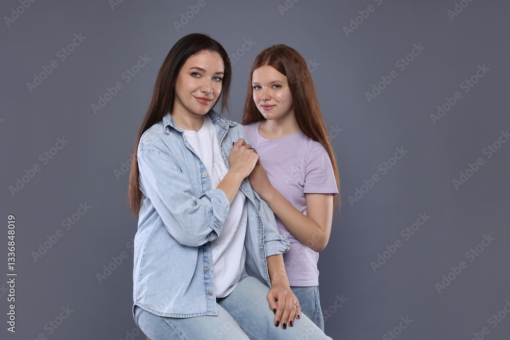 Portrait of beautiful mother with teenage daughter on grey background