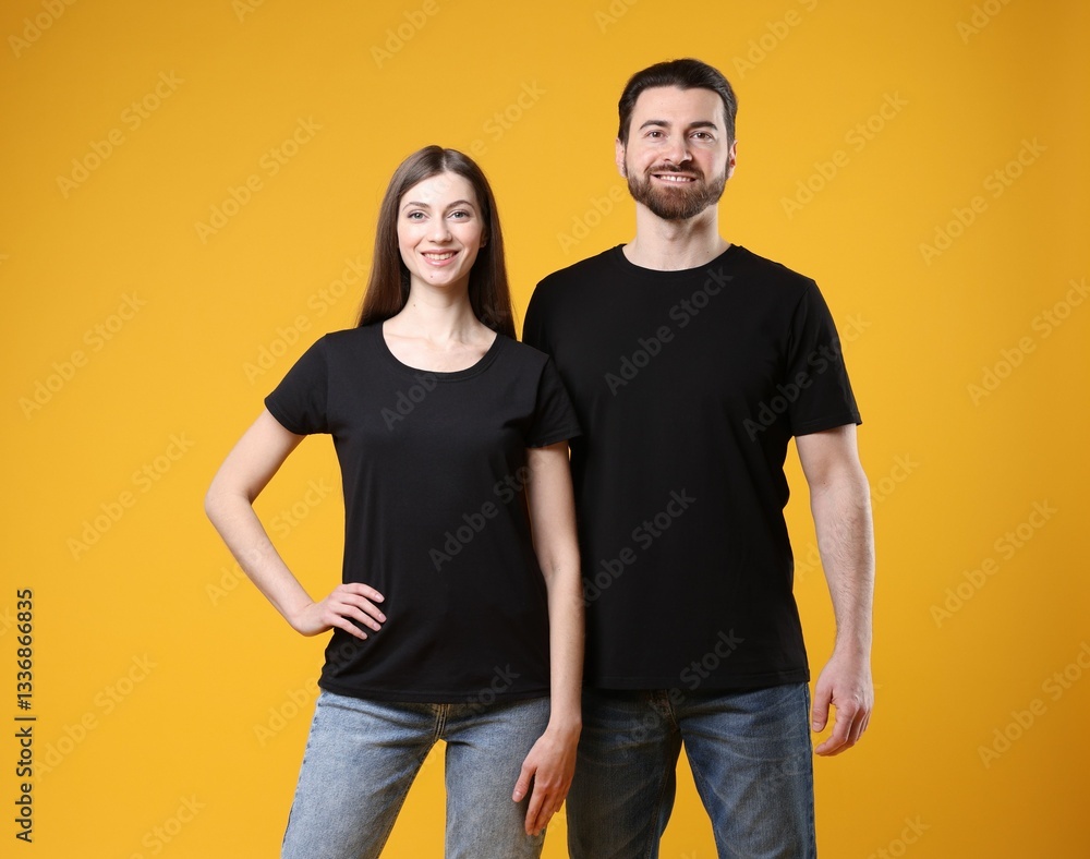 Woman and man wearing blank black t-shirts on orange background. Mockup for design Woman and man wearing blank black t-shirts on orange background. Mockup for design