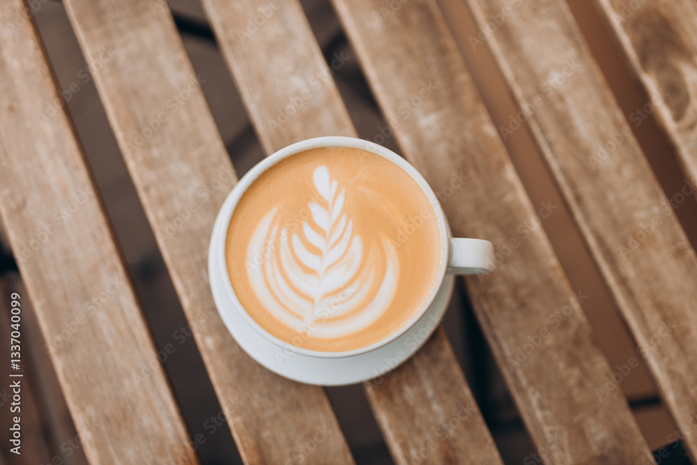 Cup of coffee on the wooden table with latte art. Street coffee, top view. Coffee in a white cup with latte art.