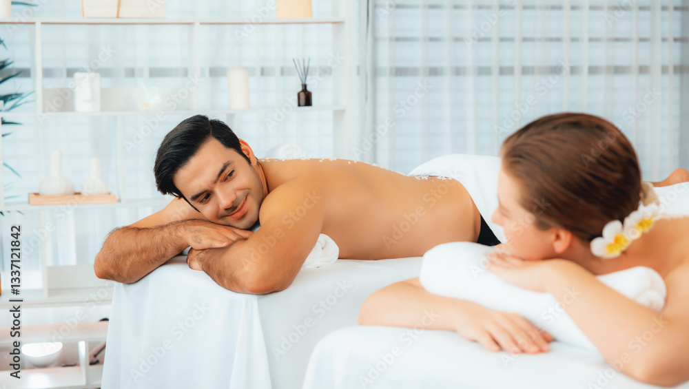 Blissful couple customer having exfoliation treatment in luxury spa salon with warmth candle light ambient. Salt scrub beauty treatment in health spa body scrub. Quiescent Blissful couple customer having exfoliation treatment in luxury spa salon with warmth candle light ambient. Salt scrub beauty treatment in health spa body scrub. Quiescent