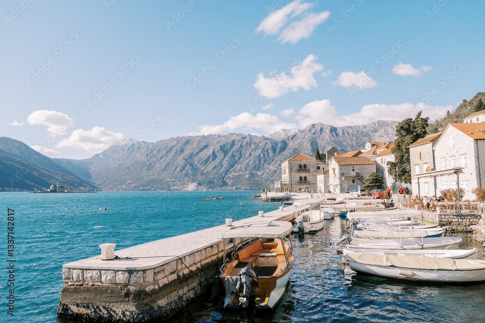 Obraz premium Row of white fishing boats is moored to a stone pier. Perast, Montenegro