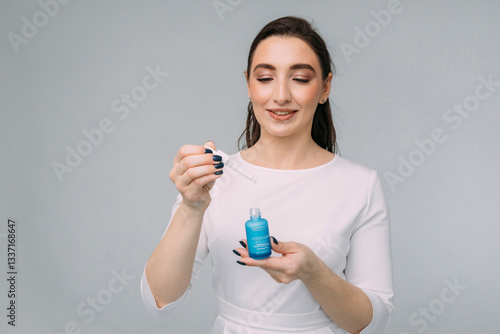 girl with long dark hair holds a bottle of cosmetic serum in her hands. Serum with retinol, niacinamide, vitamin C, anti-wrinkle