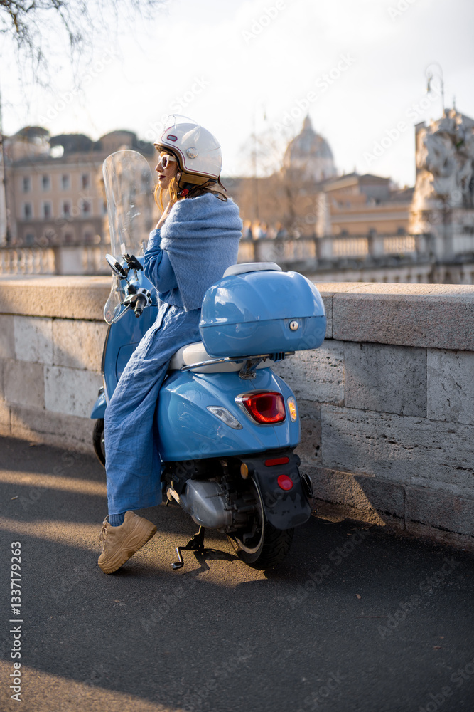 A trendy woman in a blue outfit and helmet sits on a scooter near a historic bridge in Rome, enjoying the view. The scene captures the essence of modern travel, freedom, and Italian charm