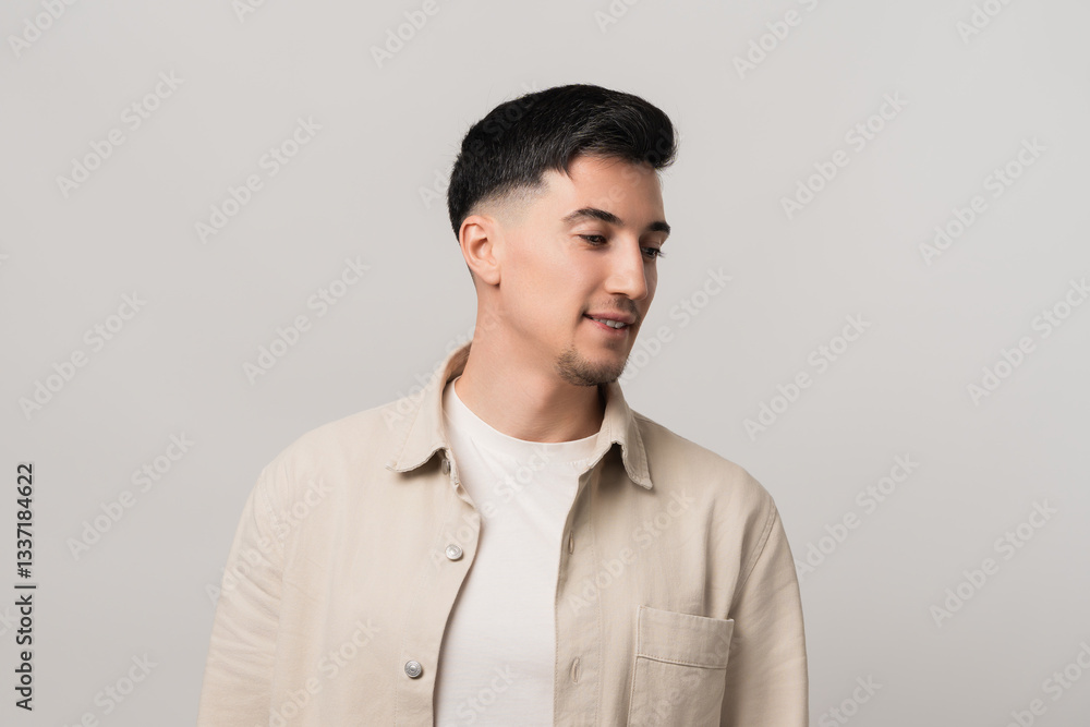 Earphones mockup blending fashion and tech. Stylish man in a beige overshirt gazing downward with a thoughtful expression, captured in a modern studio setting Earphones mockup blending fashion and tech. Stylish man in a beige overshirt gazing downward with a thoughtful expression, captured in a modern studio setting