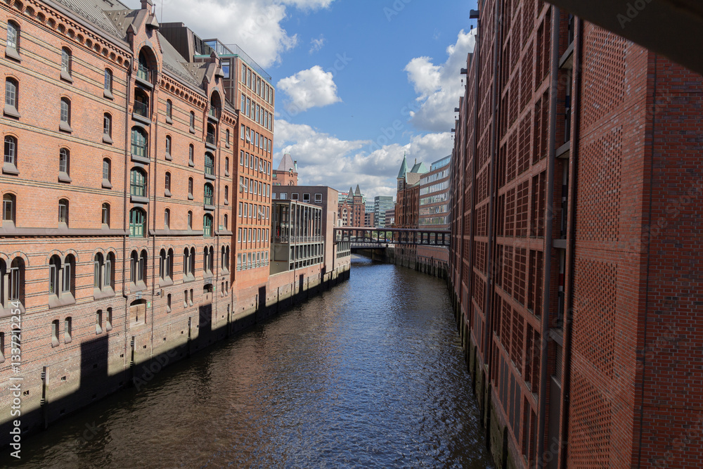 Fototapeta premium A view of the Hamburg Warehouse District (Speicherstadt), a UNESCO World Heritage site, with its red brick buildings, canals, and historic warehouses.