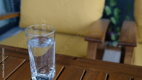Sparkling Soda Being Poured into a Glass on a Wooden Garden Table with Artificial Greenery in the Background