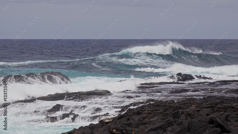 Waves crash against rocky shore under cloudy sky Waves crash against rocky shore under cloudy sky