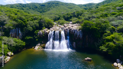 Lush green hills surround a cascading waterfall that flows into a tranquil pool