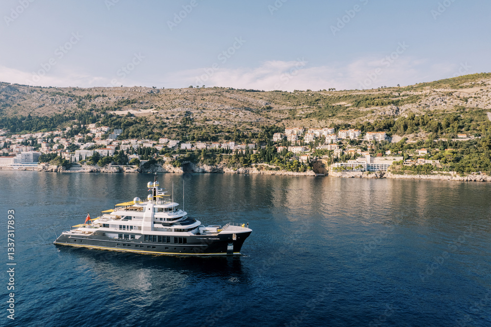 Fototapeta premium Luxury three-deck yacht sails along the mountainous coastline