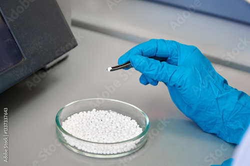 Fotografie A researcher analyzes white pellets in a laboratory, using tweezers for precise