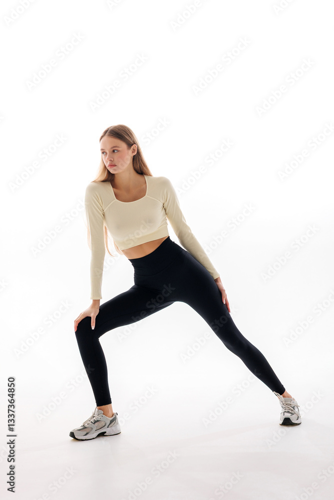 Woman practicing yoga in a bright studio performing a side stretch in athletic wear during daylight hours Woman practicing yoga in a bright studio performing a side stretch in athletic wear during daylight hours