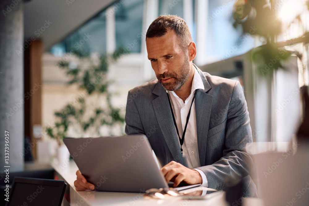 Mid adult businessman working on laptop in office. Mid adult businessman working on laptop in office.