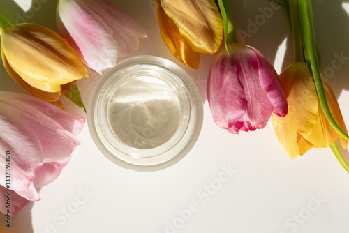 Obraz na płótnie Closeup of a jar of moisturizer surrounded by tulips. Concept of spring skincare. w salonie