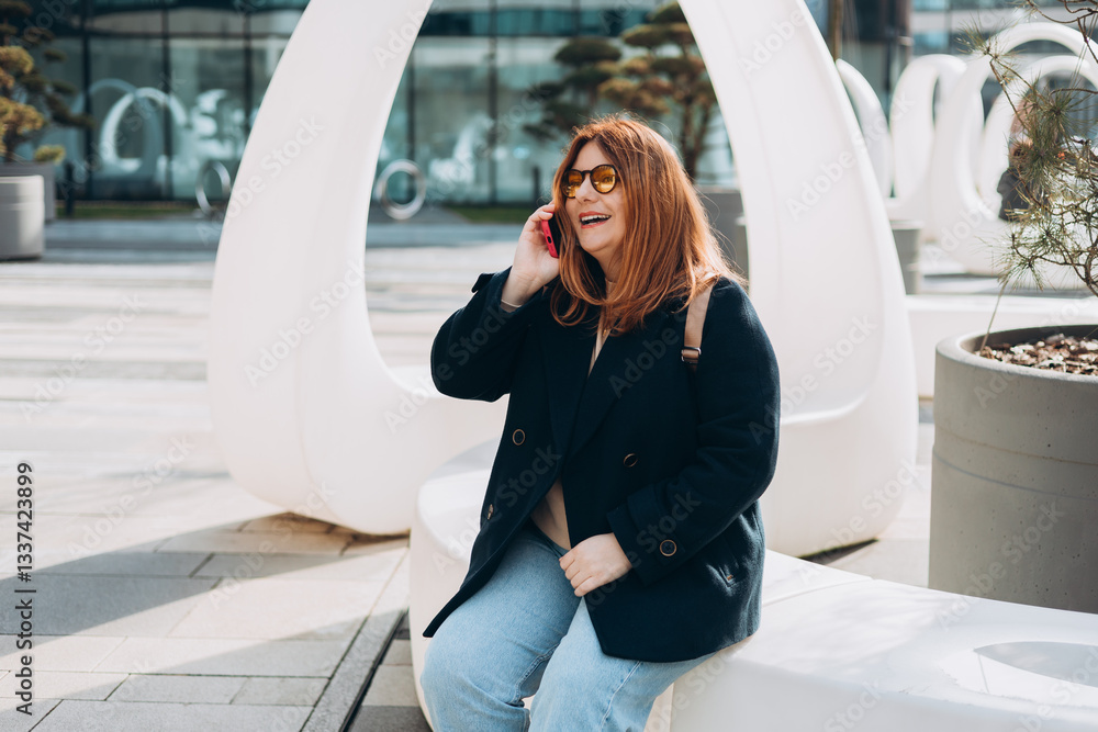Happy 30s woman talking phone and look happy outdoors. Urban lifestyle concept. Spring time. Beautiful woman walking on the modern city street.