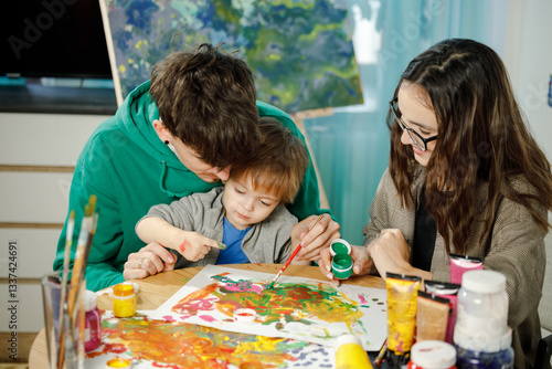 Young family with their son painting and having fun in the room