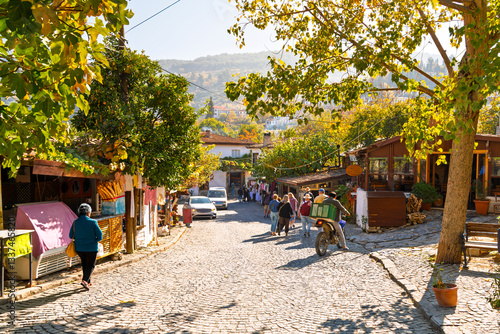 Canvas Print Tourists walk down a cobbled hillside street past shops and markets in the touristic center of the ancient village of Sirince, Turkey