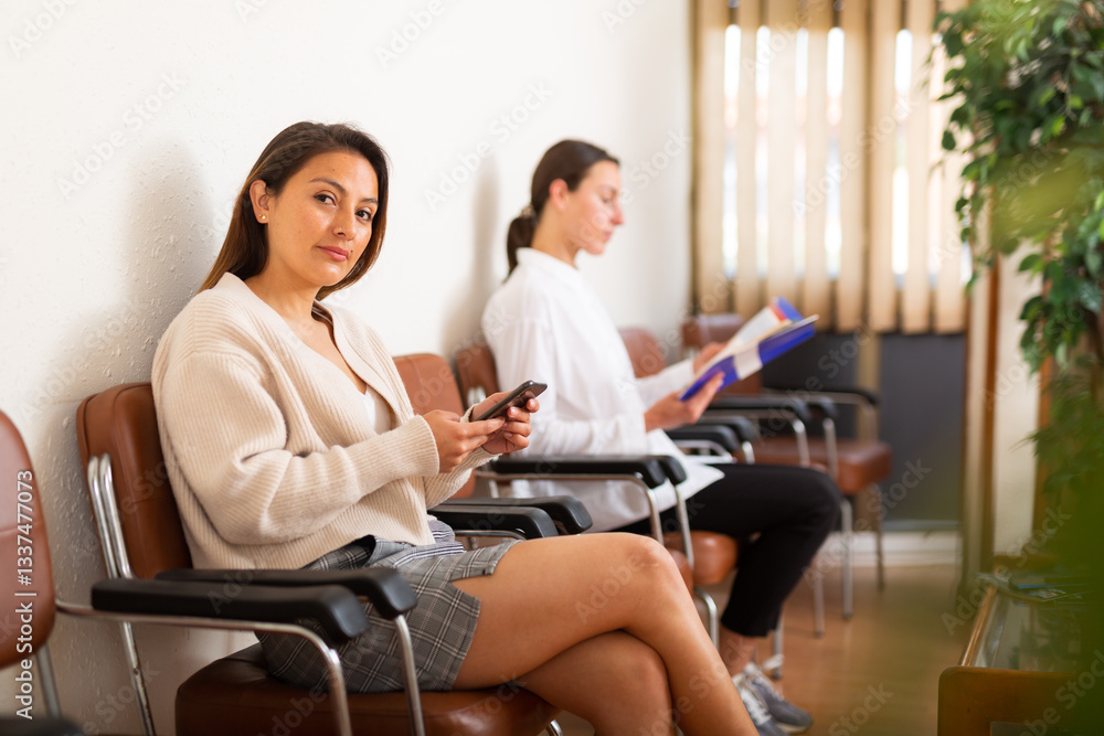 Portrait of positive woman sitting waiting at hall during visit to office of immigration services Portrait of positive woman sitting waiting at hall during visit to office of immigration services