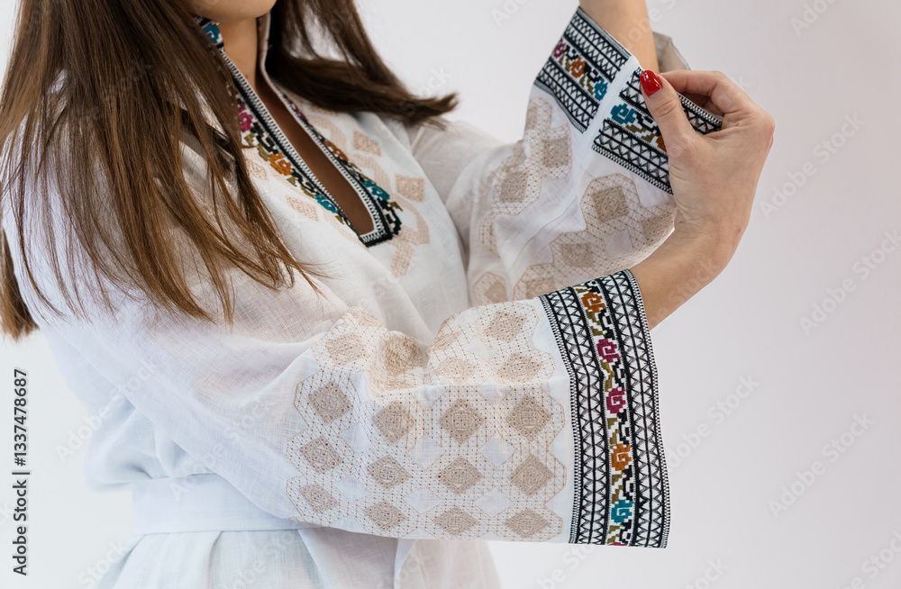 Fototapeta premium Close-up of Woman Wearing Traditional White Embroidered Dress with Colorful Ornament Details on Sleeves and Neckline