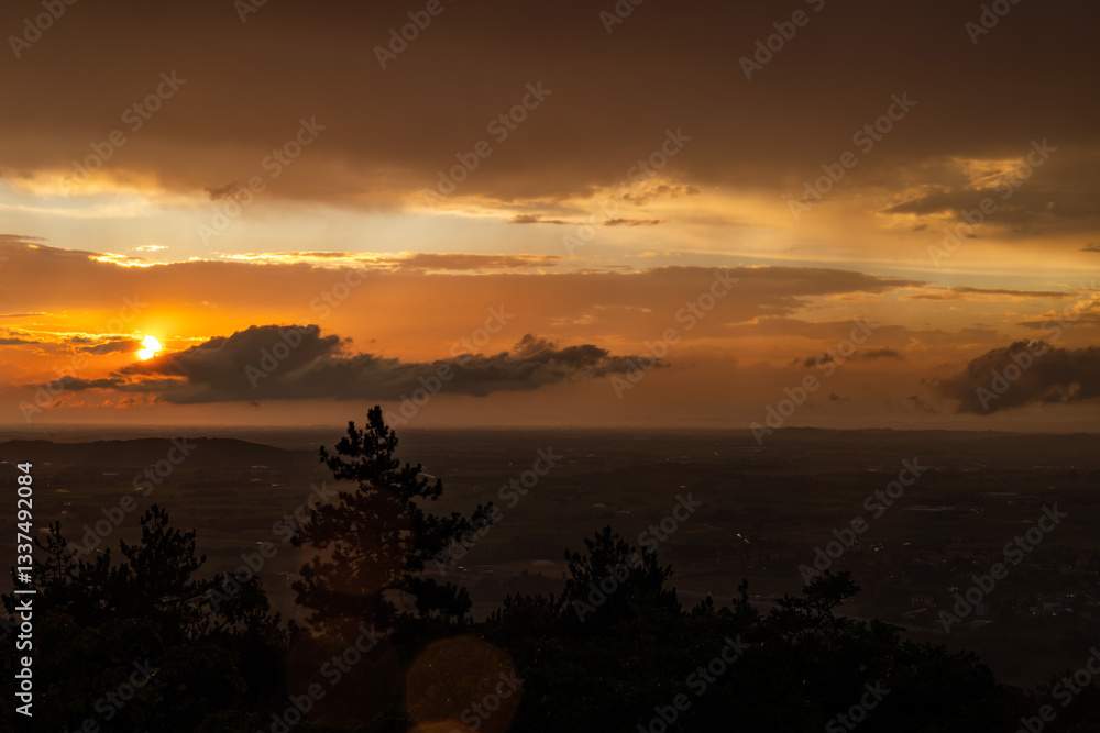 vista panoramica su parte del territorio tra pianura e collina, nella regione Friuli Venezia Giulia, dopo un temporale estivo, al tramonto, con le nuvole colorate di arancione dalla luce del sole