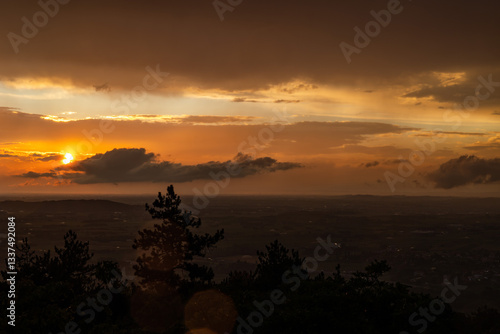 Obraz na płótnie vista panoramica su parte del territorio tra pianura e collina, nella regione Friuli Venezia Giulia, dopo un temporale estivo, al tramonto, con le nuvole colorate di arancione dalla luce del sole w salonie