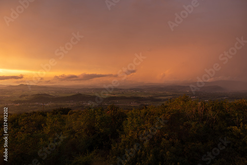 Obraz na płótnie vista panoramica su parte del territorio tra pianura e collina, nella regione Friuli Venezia Giulia, dopo un temporale estivo, al tramonto, con le nuvole colorate di arancione dalla luce del sole w salonie