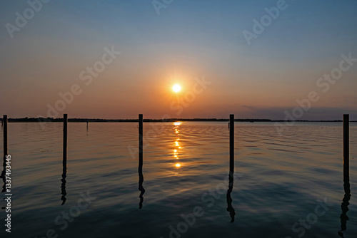Obraz na płótnie tramonto su una laguna in un ambiente marino tranquillo, nella regione Veneto, con cielo sereno, in estate, che si riflette sull'acqua w salonie