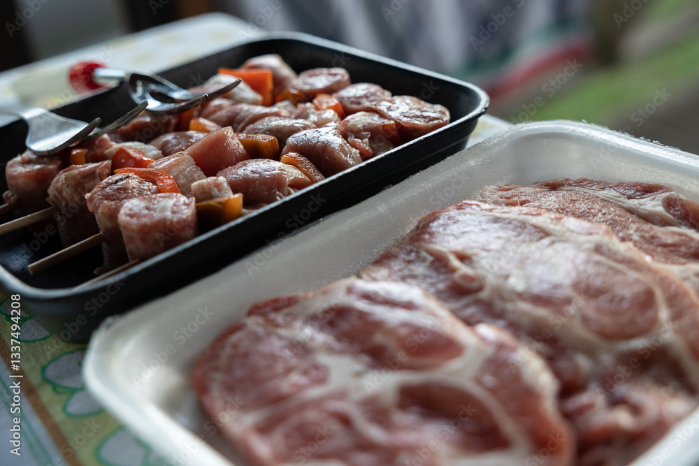 dettagli di alcuni vassoi di polistirolo che contengono degli spiedini e delle bistecche di carne, pronti per essere cucinati