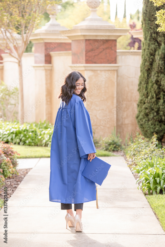 Graduate in cap and gown walking on a path Graduate in cap and gown walking on a path