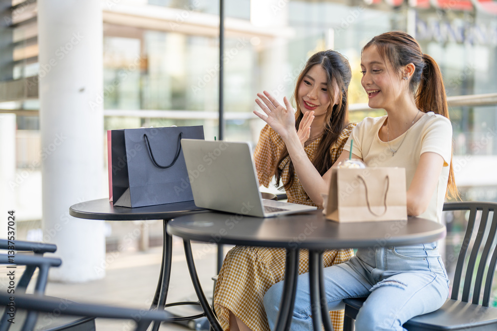 Two diverse women smiling and talking while use laptop for online shopping at cafe, searching for deals and discounts with shopping bags on table, concept of e-commerce, retail, digital lifestyle Two diverse women smiling and talking while use laptop for online shopping at cafe, searching for deals and discounts with shopping bags on table, concept of e-commerce, retail, digital lifestyle