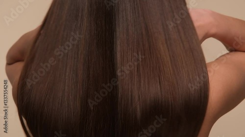 Beautiful woman with brown healthy hair on beige background. Hair beauty.