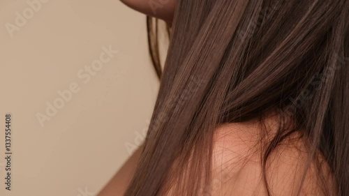 Beautiful woman with brown healthy hair on beige background. Hair beauty.