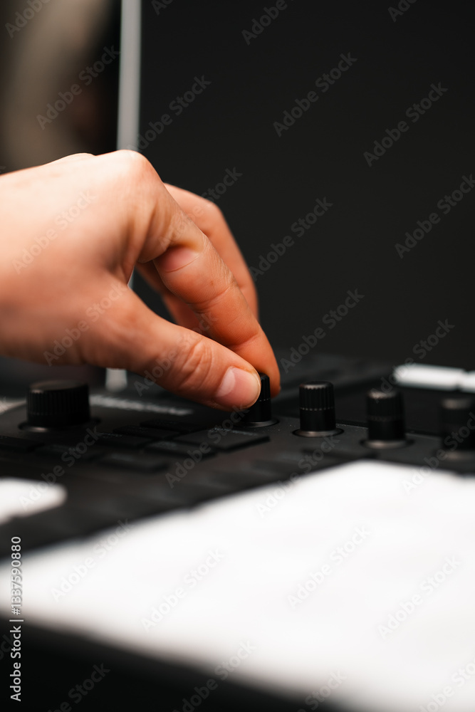 Hand turning a dial on music production equipment hardware in a studio Hand turning a dial on music production equipment hardware in a studio