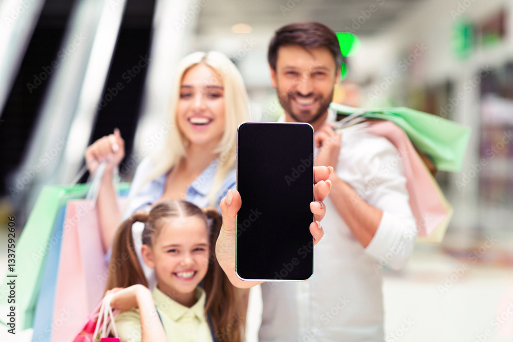 Shopping App. Happy Family Showing Blank Smartphone Screen Spending Time In Mall. Mockup, Shallow Depth Shopping App. Happy Family Showing Blank Smartphone Screen Spending Time In Mall. Mockup, Shallow Depth