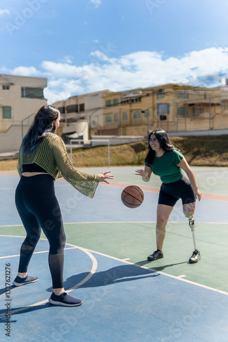 Wallpaper Mural Young women playing basketball outdoors, one with prosthetic leg, embracing inclusivity and sportsmanship Torontodigital.ca