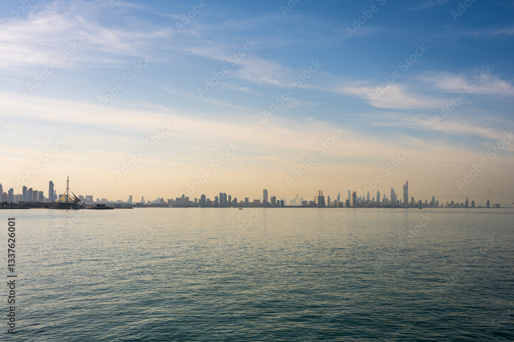 Naklejka premium Panoramic View of Kuwait City Skyline with Calm Arabian Gulf Waters and Marina Waves at Sunrise