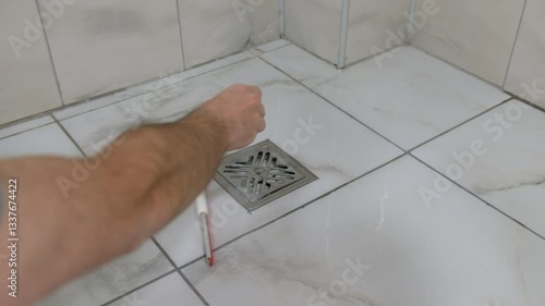 Man Cleaning Bathroom Floor with Small Mop Pushing Water Toward Drain on Marble Surface
